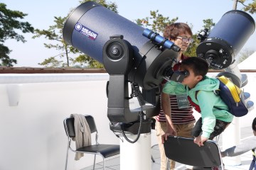 한 어린이가 반사굴절망원경을 통해 천체를 관측하고 있다.